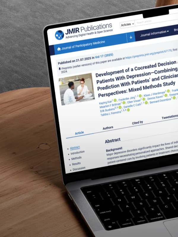 Laptop op een houten bureau toont de wetenschappelijke publicatie over de I-SHARED keuzehulp voor depressie in het Journal of Participatory Medicine