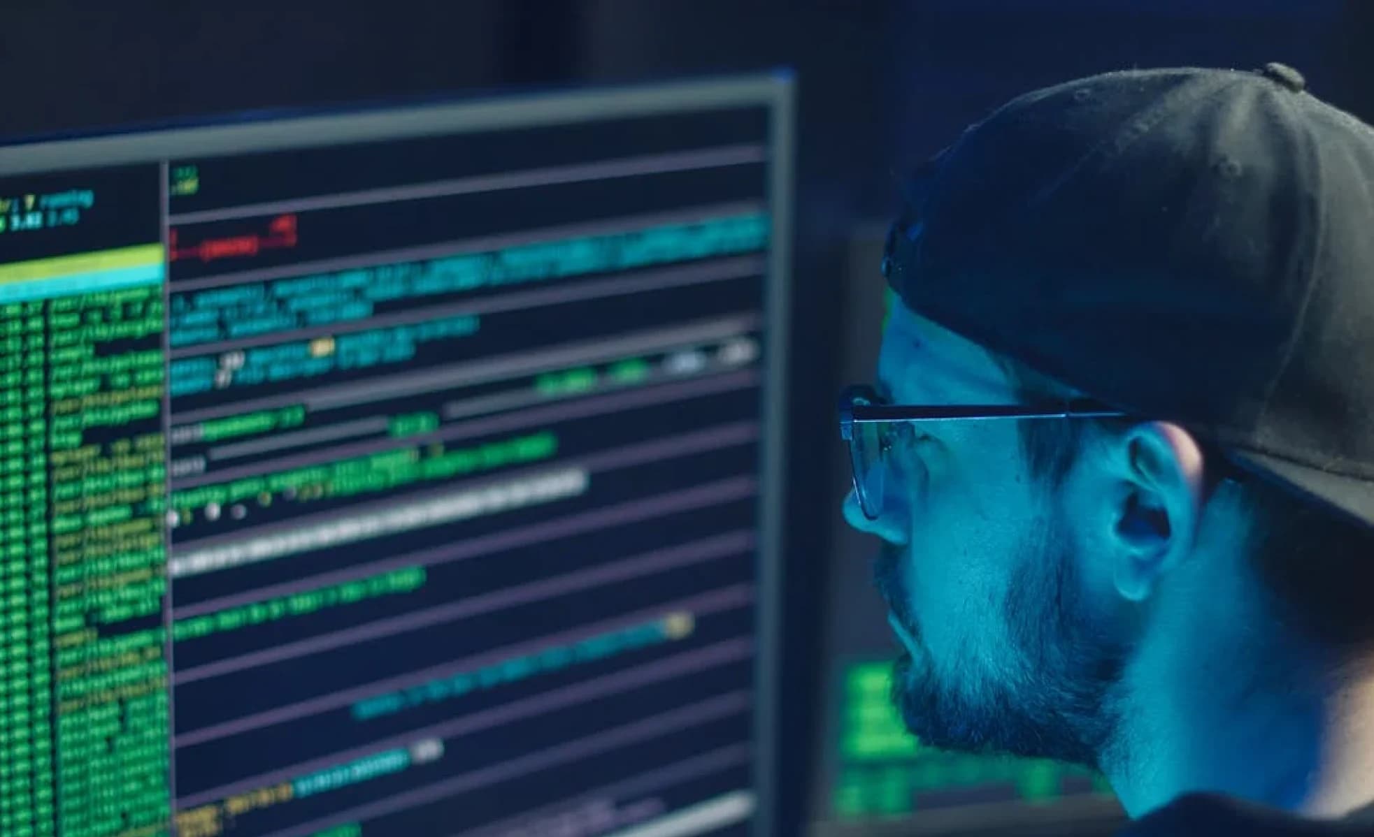 Ontwikkelaar bekijkt geconcentreerd code op een scherm in een donkere ruimte, beeld bij privacy en ethiek in data-analyse